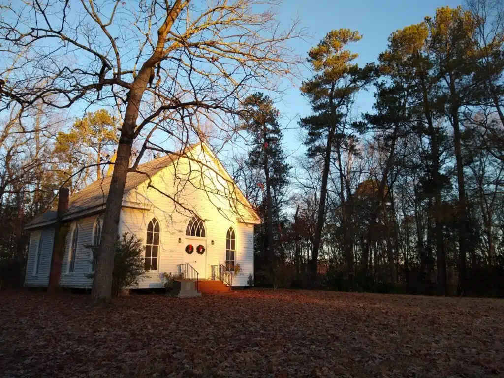 The historic O'Kelly Chapel at golden hour among winter trees in Durham, NC
