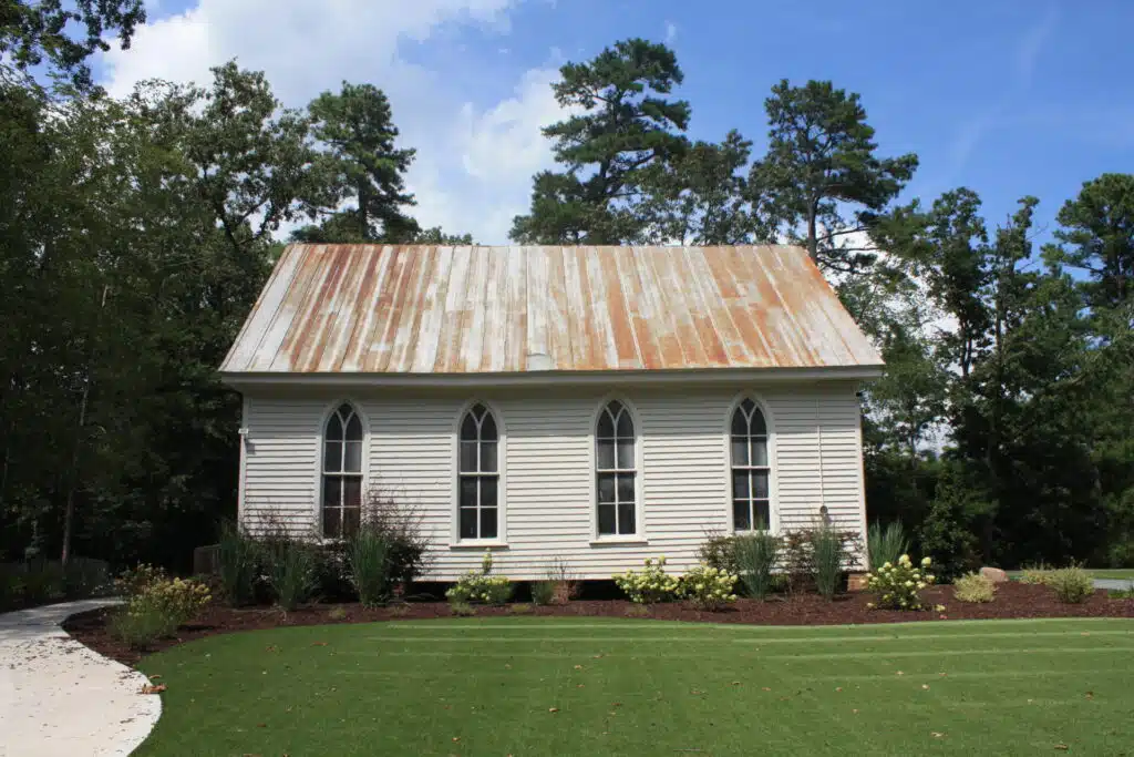 Exterior of O'Kelly Chapel, a historic white wedding venue with a tin roof in Durham, NC