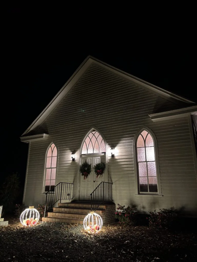 O'Kelly Chapel illuminated at night with glowing Gothic arched windows
