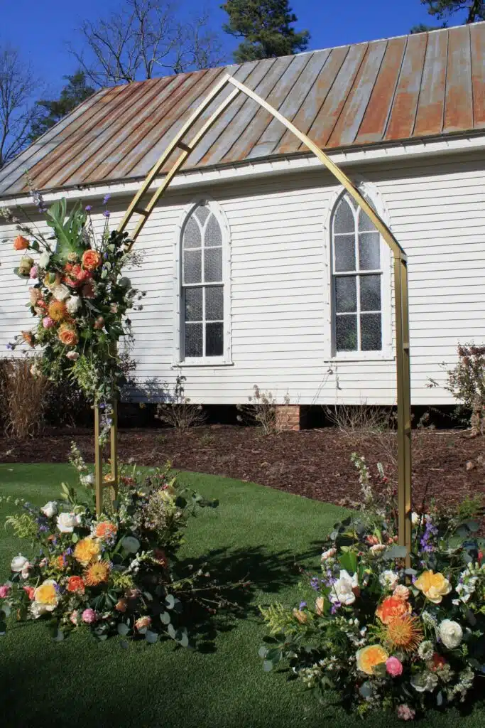 Floral wedding arch with autumn flowers beside O'Kelly Chapel