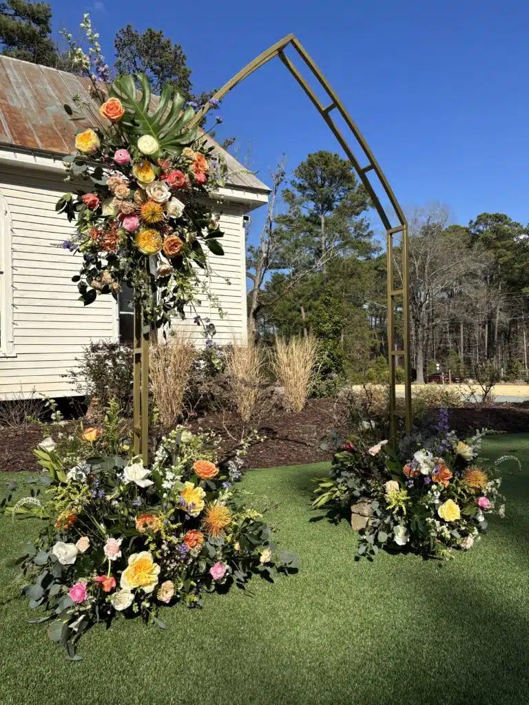 Gold floral wedding arch with autumn blooms in front of O'Kelly Chapel