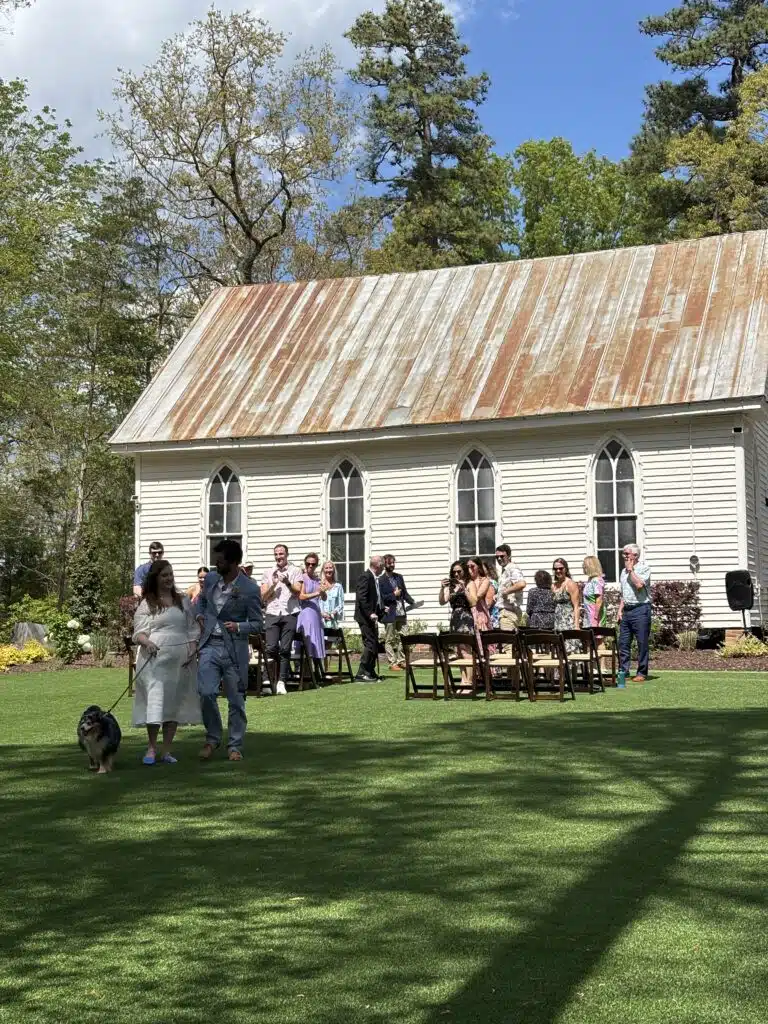 Outdoor wedding ceremony with seated guests beside O'Kelly Chapel